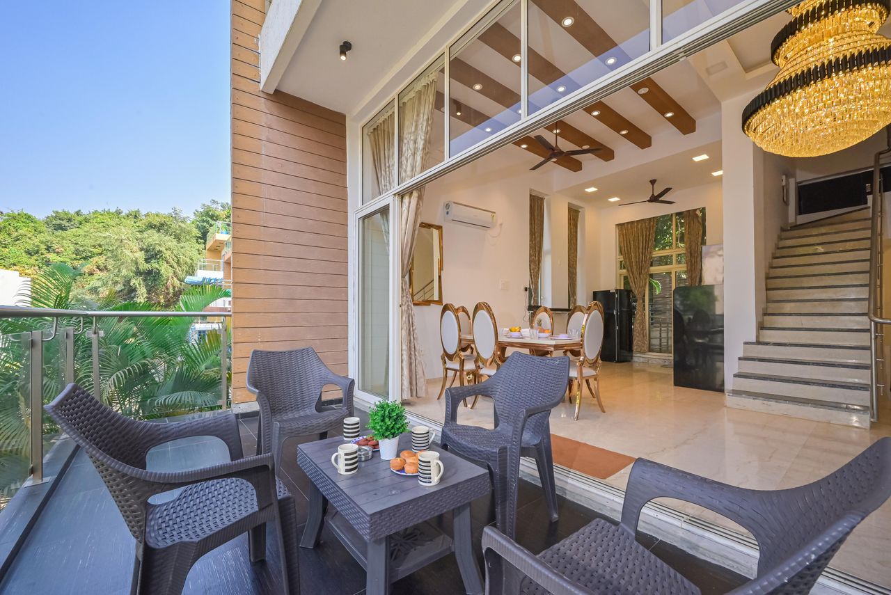 Chic indoor-outdoor space with elegant dining, cozy seating, and lush greenery.